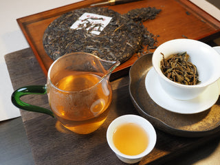 Complete Gongfu tea ceremony setup with Bulang Mountain raw pu-erh tea cake, gaiwan, and liquor