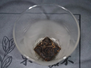 Mini-cake of Golden Flower White Tea (Fu Ding material) placed in a clear glass gaiwan, ready for first rinse.