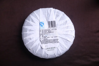 Back side of the 2018 Mengku Xiao Hu Sai Raw Pu-erh tea cake wrapper, featuring production information and official stamp.