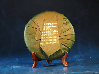 Back view of 2023 Menghai First-Flush Golden Abundance Raw Puerh Tea Cake (357g) with packaging, highlighting product label and detailed information.
