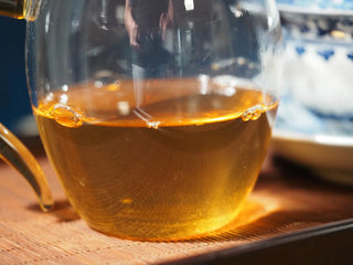 Close-up of tea liquor in the fair cup brewed from 2023 Menghai First-Flush Golden Abundance Raw Puerh Tea (357g), highlighting rich amber color.