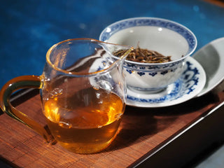 Gaiwan and fair cup side by side with 2023 Menghai First-Flush Golden Abundance Raw Puerh Tea (357g), showing bright tea liquor and leaf infusion.