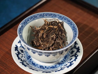 2023 Menghai First-Flush Golden Abundance Raw Puerh Tea (357g) placed in a traditional gaiwan, ready for brewing, showing vibrant dry leaves.