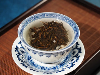 2023 Menghai First-Flush Golden Abundance Raw Pu-erh Tea (357g) fully soaking in gaiwan, leaves opening and releasing fresh aroma.