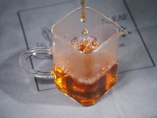 Pouring and showing the rich amber liquor color of the brewed Golden Flower White Tea, served in cups.