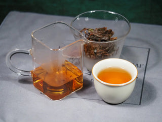 Elegant final presentation of On Taoism Golden Flower White Tea and two cups of rich amber liquor.