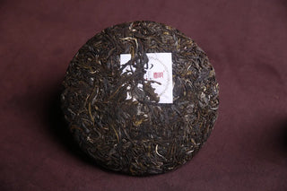 Close-up top-down view of the dark, aged 2018 Xiao Hu Sai Raw Pu-erh Tea Cake, showing compressed dry leaves.