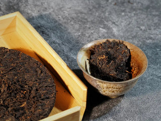 Golden Treasure Ripe Puerh Tea Cake – Menghai Origin, a portion of the tea pried from the cake placed inside a gaiwan, ready for brewing.