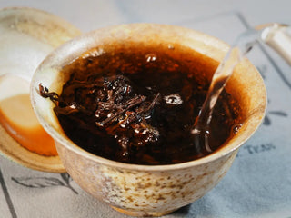 Golden Treasure Ripe Puerh Tea Cake – Menghai Origin, tea leaves fully expanded in the gaiwan as hot water fills it, revealing dark brown leaves with golden tips.