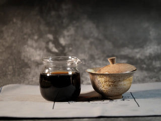 Golden Treasure Ripe Puerh Tea Cake – Menghai Origin, the brewed gaiwan and glass fairness cup placed together, highlighting the deep red tea liquor and traditional brewing setup.