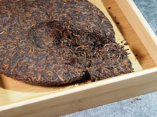 Misty Gold Bud Ripe Pu-erh Tea Cake – Menghai First-Spring-small piece of the tea cake placed beside the main cake, showing internal details with plump golden buds
