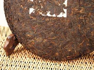 Macro detail of Jing Chang Hao Deep Velvet 2020 ripe Pu-erh cake showing compressed leaves with golden-brown tips
