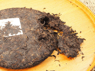 Jing Chang Hao Deep Velvet 2020 ripe Pu-erh cake broken open on a wooden tray, showing loose dark fermented leaves inside