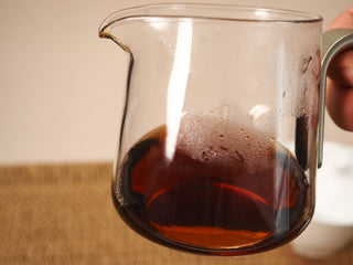 Close-up of Jing Chang Hao Deep Velvet 2020 ripe Pu-erh liquor in a glass pitcher, deep red-brown and bright