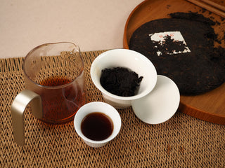 Gongfu tea session with Jing Chang Hao Deep Velvet 2020 ripe Pu-erh: glass pitcher, gaiwan of steeped leaves, cup and 357g cake