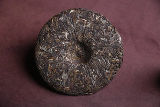 Detailed texture of the 2018 Mengku Raw Pu-erh Tea Cake showing the compressed leaves and buds (tips).