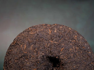 Close-up of the back surface of the bare tea cake, highlighting compressed leaf details and mid-term aged character