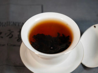 The brewed tea in the gaiwan showing a bright whiskey-like crimson liquor, clear and luminous