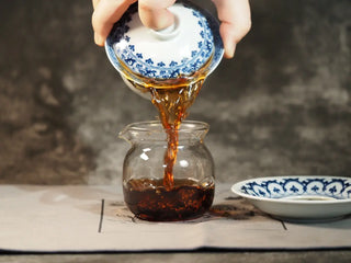 Pouring Classic 1973 Large 400g Ripe Pu-erh Tea Cake Menghai infusion into a glass fairness cup