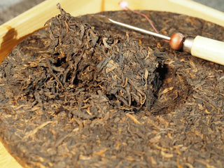 Small portion of Classic 1973 Large 400g Ripe Pu-erh Tea Cake Menghai broken off, ready for brewing