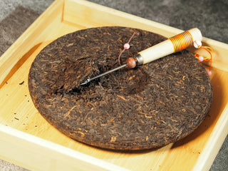 Tea needle lifting a portion of Classic 1973 Large 400g Ripe Pu-erh Tea Cake Menghai for brewing