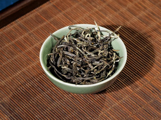 Close-up of Hengxian Dark Jasmine Needle Green Tea “Mo Xiang Zhen” in the celadon porcelain bowl at a different angle, highlighting the glossy dark leaves