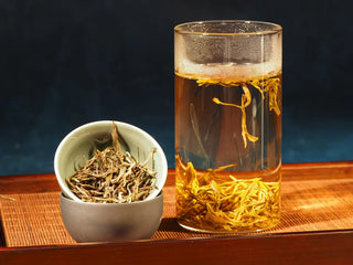 Alternate view of Hengxian Dark Jasmine Needle Green Tea “Mo Xiang Zhen” in a porcelain bowl next to a transparent glass cup, emphasizing the contrast of the dark needles and the vessel textures