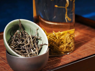 Hengxian Dark Jasmine Needle Green Tea “Mo Xiang Zhen” presented in a green porcelain bowl beside a clear glass cup filled with the same dark jasmine needle tea