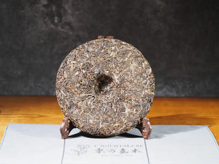 Back view of Hidden Mountain Raw Pu-erh Tea Cake (357g) unwrapped, revealing uniform yellowish tea leaves and small-batch craftsmanship.