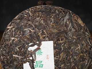 Close-up of the front of Hidden Mountain Raw Pu-erh Tea Cake (357g), highlighting dense, high-quality ancient tree leaves and pressed texture.