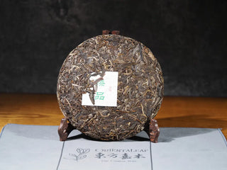 Front view of Hidden Mountain Raw Pu-erh Tea Cake (357g) without packaging, showing tightly pressed Sheng Pu-erh tea leaves from Yunnan highlands.