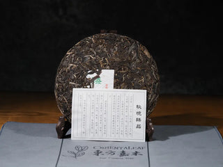 Unwrapped Hidden Mountain Raw Pu-erh Tea Cake (357g) with included product card, displaying small-scale Yunnan ancient tree tea information.