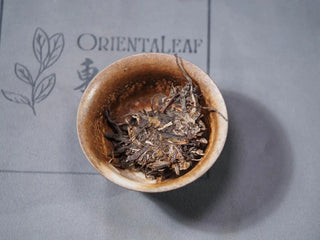 Small portion of Hidden Mountain Raw Pu-erh Tea Cake (357g) placed in a gaiwan, ready for brewing, highlighting bright yellow leaves.