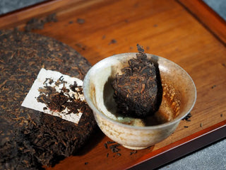 Mixiang 2017 Ripe Pu-erh Tea – MengHai Mid-Aged Golden Tip Pu-erh close-up of a small piece of tea placed in a gaiwan, showing detailed texture of the leaves