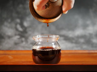 Mixiang 2017 Ripe Pu-erh Tea – MengHai Mid-Aged Golden Tip Pu-erh being poured from a gaiwan into a glass fairness cup, showing deep reddish-brown, clear tea liquor