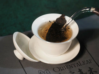 Spring Ming Ripe Pu-erh Tea Cake (2008 Commemoration) – Menghai, Yunnan pouring boiling water into a gaiwan, releasing fragrant, chocolatey aromas.