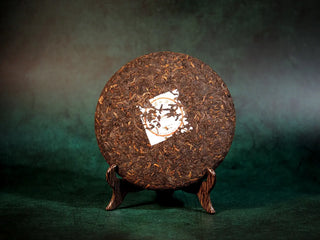 Spring Ming Ripe Pu-erh Tea Cake (2008 Commemoration) – Menghai, Yunnan unwrapped front view, displaying tightly compressed leaves with vibrant dark brown and reddish hues.