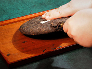 Spring Ming Large 400g Menghai Ripe Pu-erh Tea Cake – 2020 on a tea tray being carefully pried open with a tea needle.