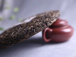 Taihua Ancient Tree Raw Puerh aged edge detail, showing dark, rich color next to Yixing teapot, premium puerh tea